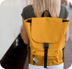 Person wearing a mustard yellow backpack with black straps and black and white NFC keychain attached to the bag