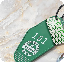 NFC keychain attached to a green hotel room key showing 'room 101' on a marble background