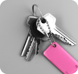 Pink NFC keychain attached to metal keys on a grey background 