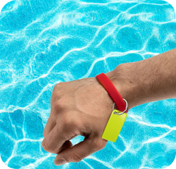 Hand with red wristband with a yellow NFC keychain attached to it against a blue pool background