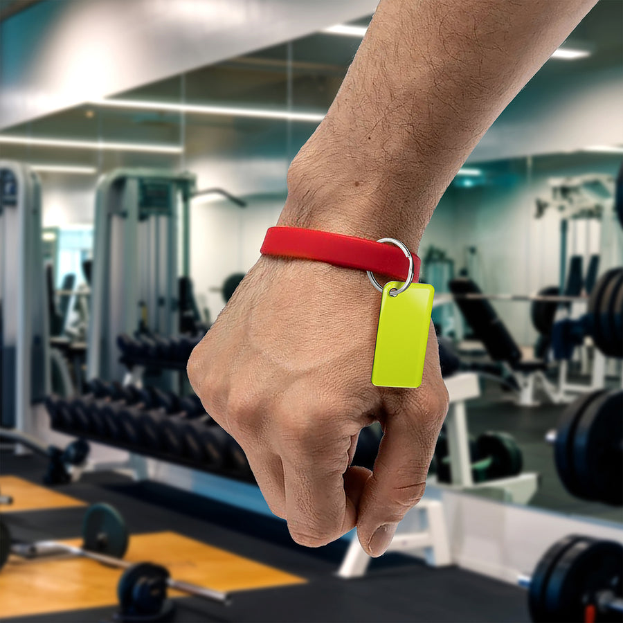 Male hand wearing a red wristband with an nfc keychain attached to it in a gym setting